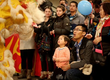 William Liu and his daughter Emily, 3, watch the Calgary Tai Chi and Martial Arts College perform the Lion Dance and hand out red envelopes during the opening ceremonies of the 2016 Year of the Monkey Chinese New Year Carnival at the Chinese Cultural Centre.