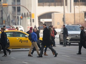 Pedestrians walk across 6th Ave. S.W. in front of turning cars in Calgary on Wednesday, Jan. 20.