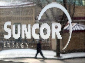 A pedestrian is reflected in a Suncor Energy sign in Calgary.