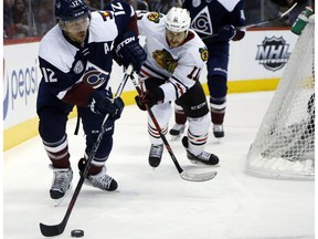 Colorado Avalanche right wing Jarome Iginla, front, tries to clear the puck from behind the net as Chicago Blackhawks center Andrew Desjardins pursues in the second period of an NHL hockey game Thursday, Dec. 31, 2015, in Denver.