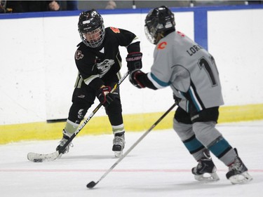 Crowfoot Coyotes Novice player Alaric Chen, left, carried the puck down the ice against Symons Valley Novice 3 player Elle Lorenz during their Esso Minor Hockey Week game.