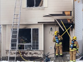 Firefighters work on dousing a house fire at a home on Martinbrook Place NE on January 13, 2016.