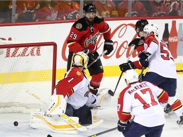 The puck slipped past Florida Panthers goalie Roberto Luongo on a shot by Calgary Flames centre Sam Bennett, obsucured as he was checked by Panthers centre Corban Knight, for his third of the game as Flames teammate defenceman Deryk Engelland, left, during first period NHL action at the Scotiabank Saddledome on January 13, 2016.