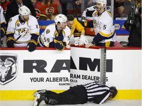 Nashville Predators' players look over the bench at linesman Don Henderson after he was hit by Calgary Flames' Dennis Wideman during second period NHL hockey action in Calgary,  on  Jan. 27, 2016.