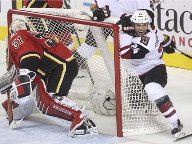 Arizona Coyotes Kyle Chipchura looks unimpressed as he hangs off the Flames net after a good shove from a Flames player during game action at the Scotiabank Saddledome in Calgary, on January 7, 2016.