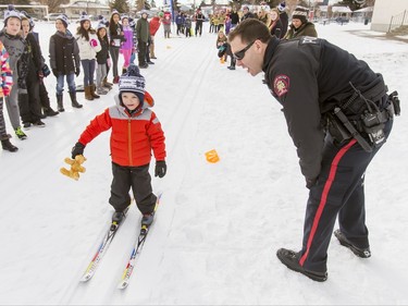 Const. Denis McHugh encourages Nolan Akitt, 6, as he skis by at Mount View School in Calgary, Alta., on Tuesday, Jan. 26, 2016. The Calgary Fire Department and Calgary Police Service, along with a pair of Olympians, went head-to-head in a relay race for an announcement by AltaGas to support Cross Country Ski de Fond Canada's Ski at School program for the next three years. Lyle Aspinall/Postmedia Network