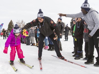 Const. Roy Moe helps Alexis Ruddick, 6, to her feet while racing her on cross-country skis at Mount View School in Calgary, Alta., on Tuesday, Jan. 26, 2016. The Calgary Fire Department and Calgary Police Service, along with a pair of Olympians, went head-to-head in a relay race for an announcement by AltaGas to support Cross Country Ski de Fond Canada's Ski at School program for the next three years. Lyle Aspinall/Postmedia Network