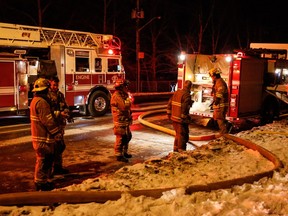 Firefighters stand outside a house fire in the 2800 block of 14th Street N.W. in Calgary on Sunday, Jan. 3, 2016.