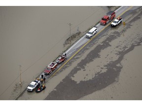 In this aerial photo, rescue personnel wait on a flooded road Wednesday, Dec. 30, 2015, in West Alton, Mo. A rare winter flood threatened nearly two dozen federal levees in Missouri and Illinois on Wednesday as rivers rose, prompting evacuations in several places.