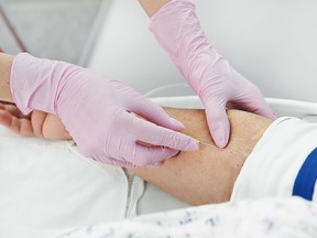 Doctor hands in protective gloves inserting a needle in a patient's arm.