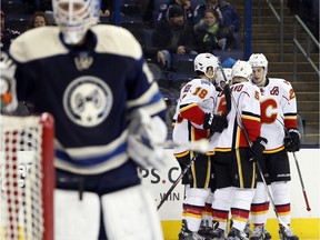 Calgary Flames players celebrate a goal against Columbus Blue Jackets' Joonas Korpisalo, of Finland, during the third period on Thursday night.