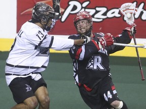 Roughneck forward Dane Dobbie, right, powers through Edmonton Rush defence Jeff Cornwall at the Scotiabank Saddledome in Calgary on Saturday, May 23, 2015.