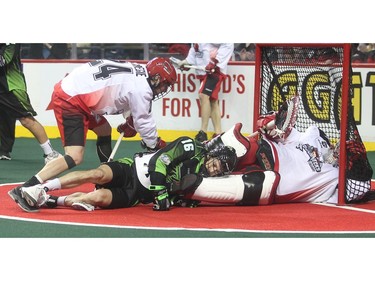 Scott Carnegie of the Calgary Roughneck knocks down Saskatchewan Rush attacker Chris Corbeil as he crashes goalie Frankie Scigliano Saturday during their home opening 10-8 loss Saturday night January 2, 2016 at the Saddledome.