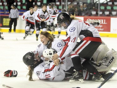 Northern Capitals players, from left to right, Sage Desjardins, Taylor Beck and Marissa Nichol mobbed goalie Kelsey Roberts after they defeated toe Rocky Mountain Raiders during the Mac's AAA Midget female final at the Scotiabank Saddledome on January 1, 2016. The Capitals defeated the Raiders 5-1 to take the 2015 title.