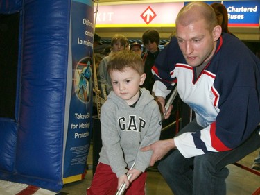 CAL0309-Calgary Flame Robyn Regehr helps Evan MacDonald,4 with his hockey skills during Minor Hockey Night raising awarness about meningitis at the Pengrowth Saddledome, Sunday. Photo Leah Hennel, Calgary Herald for Sports story by ?