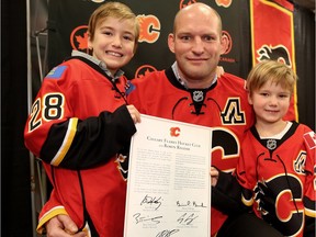 Robyn Regehr and his children Wyatt, 7, left and Shane, 4, pose for a photo with his one-day contract, which he signed in order to retire as a Calgary Flame during a press conference at the Scotiabank Saddledome on Monday.