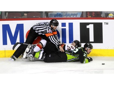 While trying to dig the puck away from the boards Hitmen Taylor Sanheim, 23, and Oil Kings Tyler Roberston almost took down the referee as the Calgary Hitmen played host to the Edmonton Oil Kings on Saturday, January 16, 2016 at the Saddledome.