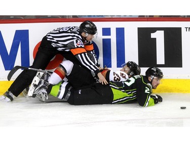 While tryingto dig the puck away from the boards Hitmen Taylor Sanheim, 23, and Oil Kings Tyler Roberston almost took down the referee as the Calgary Hitmen played host to the Edmonton Oil Kings on Saturday, January 16, 2016 at the Saddledome.
