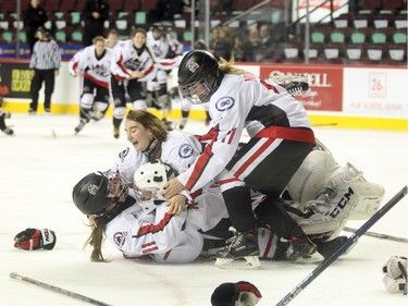 Northern Capitals players, from left to right, Sage Desjardins, Taylor Beck and Marissa Nichol mobbed goalie Kelsey Roberts after they defeated toe Rocky Mountain Raiders during the Mac's AAA Midget female final at the Scotiabank Saddledome on January 1, 2016. The Capitals defeated the Raiders 5-1 to take the 2015 title.