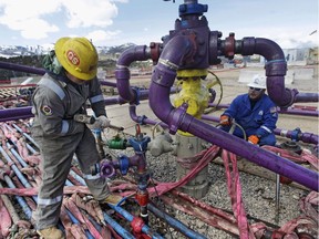 Workers tend to a well head at an Encana fracking gas well outside Rifle, in western Colorado.