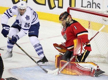 Calgary Flames goalie Jonas Hiller, right, blocks a shot from  Toronto maple Leafs Daniel Winnik in NHL hockey action at the Scotiabank Saddledome in Calgary, Alta. on Tuesday February 9, 2016. Leah Hennel/Postmedia