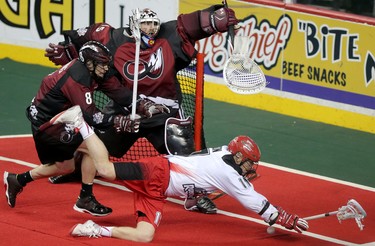 Colorado Mammoth Greg Downing, left and Calgary Roughnecks Curtis Dickson, right,  battle for the ball in front of Mammoth netminder Dillon Ward during game action at the Scotiabank Saddledome in Calgary, Alta. on Saturday February 13, 2016. Leah Hennel/Postmedia