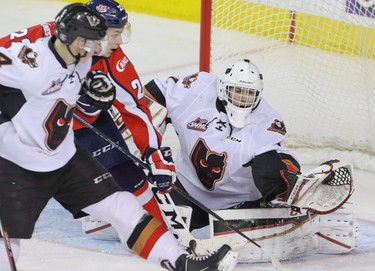 Calgary Hitmen goalie Nik Amundrud gets his glove on a shot as Lethbridge Hurricanes Egor Babenko and Hitmen Micheal Zipp look for the rebound in WHL action at the Scotiabank Saddledome in Calgary, Alberta, on Saturday, February 20, 2016. The Hitmen beat the Hurricanes 3-2. Mike Drew/Postmedia