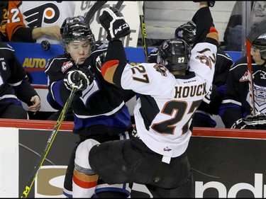Calgary Hitmen Jackson Houck collides with Victoria Royals Marsel Ibragimov in front of the Royals bench in WHL action at the Scotiabank Saddledome in Calgary, Alberta, on Friday, February 26, 2016. Mike Drew/Postmedia