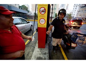A motorcyclist pays about two Bolivars (3 cents of a dollar) after filling his scooter's tank at a gas station in Caracas, Venezuela, Wednesday, Feb. 17, 2016. Venezuela's government is raising gasoline prices sixtyfold, the first increase of any kind in more than 17 years as the country struggles with an economic collapse. Yet drivers will still be able to fill their tanks for pennies.