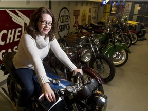 Barb Munro, Heritage Park's public relations gal, mugs for a photo with motorcycles arriving at the park's Gasoline Alley in Calgary, Alta., on Thursday, Jan. 21, 2016.