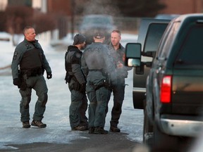 Police tactical team members pack up gear after a standoff ended in arrests at Templebow Place N.E. in Calgary early Wednesday morning February 3, 2016.