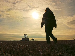Kelly Nelson walks near an oil pump jack on the farm she owns with her husband Gord east of Arrowwood, Alberta.