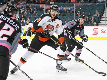 Medicine Hat Tigers captain Ty Stanton looks to pass between the The Calgary Hitmen's Mark Kastelic left and Carsen Twarynski during WHL action at the Scotiabank Saddledome on Sunday February 21, 2016.