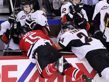 Calgary Hitmen Carsen Twarynski checks the Portland Winterhawks' Tanner Nagel into the bench scoring during first period WHL action at the Scotiabank Saddledome on Tuesday February 23, 2016.