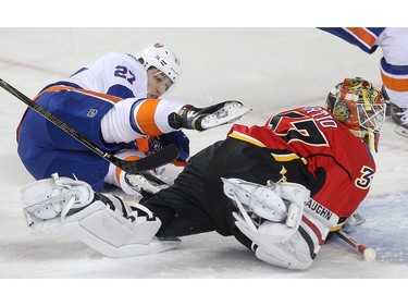 Calgary Flames goalie Joni Ortio covers up the puck on Anders Lee of the New York Islanders in the first period behind the Flames net at the Saddledome Thursday night February 25, 2016.