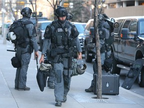 A Calgary Police Tactical Unit member carries equipment as police execute a search warrant at a downtown Calgary, Alta apartment building on Thursday, Feb. 25, 2016