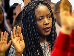 Cynthia Magwagwa takes the oath as the Canadian Club of Calgary welcomes 90 new citizens in celebration of National Flag of Canada Day in Calgary on Monday, Feb. 15, 2016. Mike Drew/Postmedia