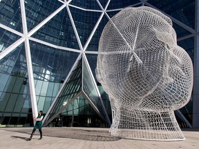 A woman walks by the sculpture 'Wonderland' in front of the Bow building, home to Encana Corporation, in downtown Calgary on Wednesday, Feb. 24, 2016. Encana plans tor educe 20 per cent of its workforce en route to $250 million in additional cost savings this year, beyond what had previously been announced.