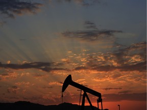 The sun sets behind an oil pump in the desert oil fields of Sakhir, Bahrain.