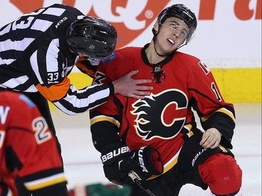 Referee Kevin Pollock checks on Johnny Gaudreau of the Calgary Flames after taking a stick to the face during a game against the Minnesota Wild in NHL hockey in Calgary, Alta., on Wednesday, February 17, 2016. Al Charest/Postmedia