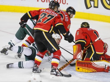 Nino Niederreiter of the Minnesota Wild falls between Dougie Hamilton and Deryk Engelland of the Calgary Flames in front of goalie Jonas Hiller in Calgary, Alta., on Wednesday, Feb. 17, 2016. Lyle Aspinall/Postmedia Network