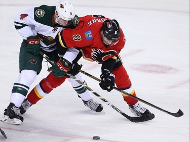 Minnesota Wild Mike Reilly and Joe Colborne of the Calgary Flames battle for a loose puck during NHL hockey in Calgary, Alta. on Wednesday February 17, 2016. Al Charest/Postmedia