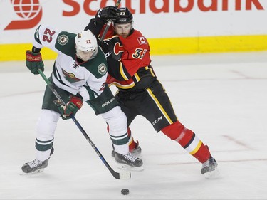 Nino Niederreiter of the Minnesota Wild battles for a puck with Jakub Nakladal of the Calgary Flames in Calgary, Alta., on Wednesday, Feb. 17, 2016. Lyle Aspinall/Postmedia Network