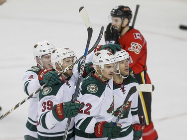 Mike Reilly, Nate Prosser, Nino Niederreiter and Jason Pominville of the Minnesota Wild celebrate a goal near Jakub Nakladal of the Calgary Flames in Calgary, Alta., on Wednesday, Feb. 17, 2016. Lyle Aspinall/Postmedia Network