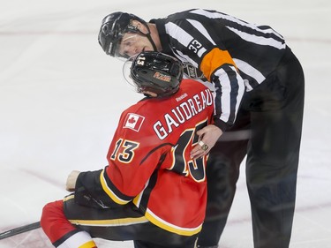 Referee Kevin Pollock checks on Johnny Gaudreau of the Calgary Flames as he's slow to get up during action against the Minnesota Wild in Calgary, Alta., on Wednesday, Feb. 17, 2016. Lyle Aspinall/Postmedia Network