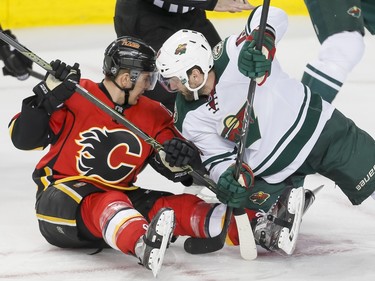 Mikael Backlund of the Calgary Flames and Jarret Stoll of the Minnesota Wild hit the ice after a faceoff in Calgary, Alta., on Wednesday, Feb. 17, 2016. Lyle Aspinall/Postmedia Network