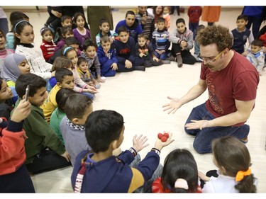 James Jordan, with the Green Fools Theatre Society, right, does magic tricks for Syrian refugee children.