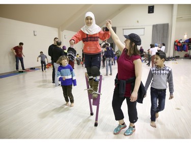 Judith Mendelsohn, with the Green Fools, right, helps Syrian refugee children play at a rec-centre in Calgary, Ab., on Tuesday February 23, 2016.