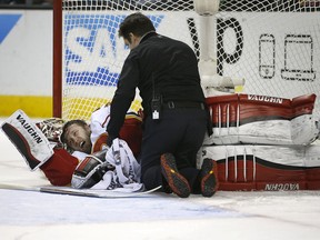 Calgary Flames goalie Karri Ramo is checked on by a trainer after Ramo's collision with San Jose Sharks' Joonas Donskoi during the third period.