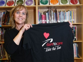 Lisa Dixon-Wells, founder of  the "Dare to Care" anti-bullying program, poses with a T-shirt after she presented a 45-minute program to students at Valley Creek School in northwest Calgary on Tuesday, Feb. 23, 2016.